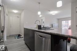 Kitchen with stainless steel appliances, hanging light fixtures, light wood-style flooring, light countertops, and modern cabinets - 