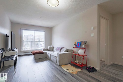 Living room with light wood-style flooring and a textured ceiling - 236 344 Windermere Road, Edmonton, AB - Indoor