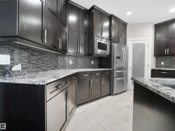 Kitchen with appliances with stainless steel finishes, decorative backsplash, light stone countertops, recessed lighting, and light tile patterned floors - 