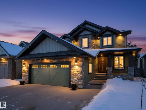 View of front of house with stone siding, an attached garage, a porch, and driveway - 59 10550 Ellerslie Road, Edmonton, AB - Outdoor With Facade