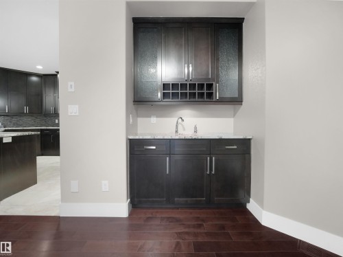 Bar featuring wood finish floors, light stone counters, backsplash, and recessed lighting - 59 10550 Ellerslie Road, Edmonton, AB - Indoor