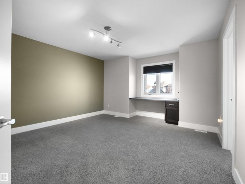 Unfurnished room featuring light colored carpet, built in study area, and rail lighting - 59 10550 Ellerslie Road, Edmonton, AB - Indoor Photo Showing Other Room