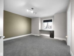 Unfurnished room featuring light colored carpet, built in study area, and rail lighting - 