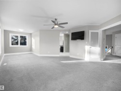 Unfurnished living room featuring arched walkways, light colored carpet, and ceiling fan - 