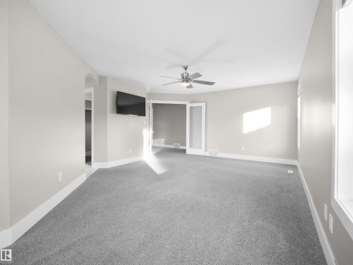 Spare room featuring carpet flooring and arched walkways - 59 10550 Ellerslie Road, Edmonton, AB - Indoor Photo Showing Other Room