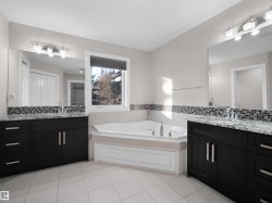 Bathroom featuring tasteful backsplash, two vanities, a bath, and light tile patterned flooring - 