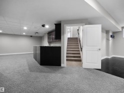 Indoor wet bar with dark carpet, dark cabinets, stairway, glass insert cabinets, and recessed lighting - 
