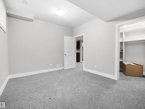 Unfurnished bedroom featuring a spacious closet and light carpet - 59 10550 Ellerslie Road, Edmonton, AB - Indoor Photo Showing Other Room