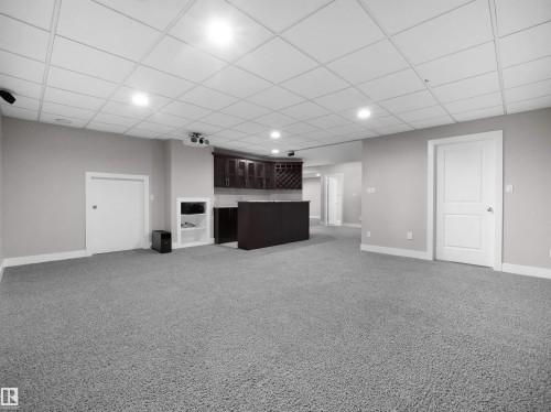 Unfurnished living room featuring a paneled ceiling, light colored carpet, recessed lighting, and bar - 59 10550 Ellerslie Road, Edmonton, AB - Indoor