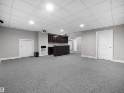 Unfurnished living room featuring a paneled ceiling, light colored carpet, recessed lighting, and bar - 