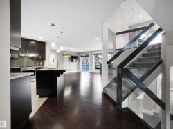 Kitchen featuring open floor plan, hanging light fixtures, stainless steel stove, dark wood-style flooring, and dark brown cabinetry - 