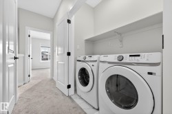 Laundry area featuring washing machine and dryer, light marble finish floors, and light colored carpet - 