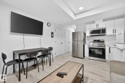 Kitchen featuring light countertops, stainless steel appliances, white cabinetry, and light wood finished floors - 