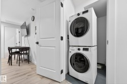Washroom with light wood-style flooring and stacked washing machine and dryer - 