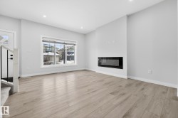 Unfurnished living room featuring a glass covered fireplace, light wood-type flooring, stairs, and recessed lighting - 