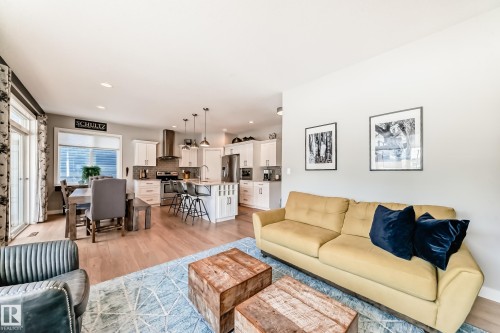 Open concept living area featuring hardwood flooring, recessed lighting, and a kitchen with white cabinetry and stainless steel appliances - 11 Etoile Cres N, St. Albert, AB - Indoor Photo Showing Living Room