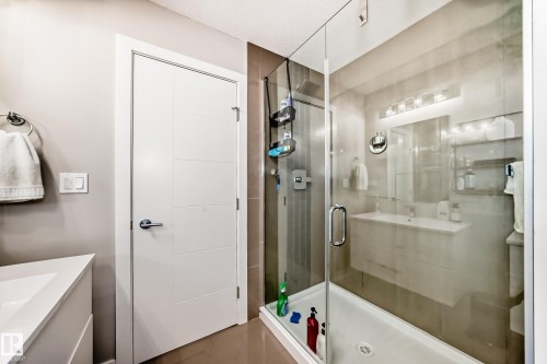 The bathroom features a glass-enclosed shower with tile walls and a modern vanity with a large mirror and overhead lighting - 11 Etoile Cres N, St. Albert, AB - Indoor Photo Showing Bathroom