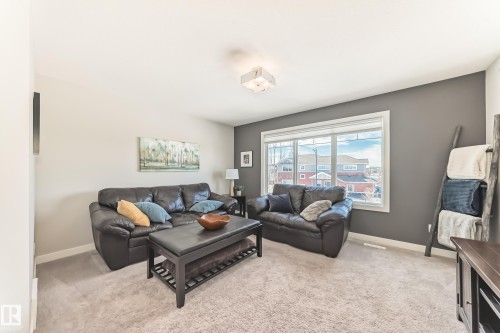 This living space features soft carpet flooring, light-colored walls, and a large window offering natural light - 11 Etoile Cres N, St. Albert, AB - Indoor Photo Showing Living Room
