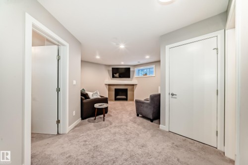 The property features a cozy living space with carpeted flooring, recessed lighting, and a fireplace with a mantel - 11 Etoile Cres N, St. Albert, AB - Indoor