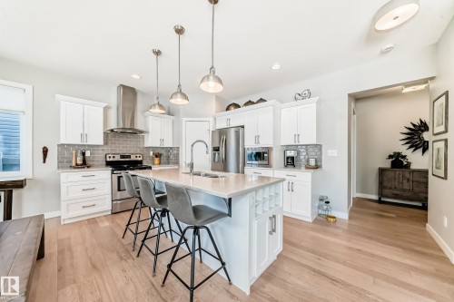 The kitchen features white cabinetry, stainless steel appliances, and a central island with a light-colored countertop - 11 Etoile Cres N, St. Albert, AB - Indoor Photo Showing Kitchen With Stainless Steel Kitchen With Upgraded Kitchen