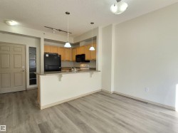 Kitchen with black appliances, a breakfast bar, a peninsula, hanging light fixtures, and a textured ceiling - 