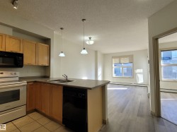 Kitchen with black appliances, open floor plan, hanging light fixtures, a textured ceiling, and a peninsula - 