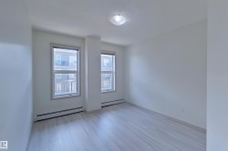 Unfurnished room featuring a baseboard heating unit and wood finished floors - 