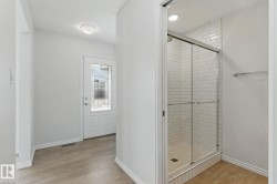 The entrance features light-colored flooring and a white door with decorative glass inserts - 