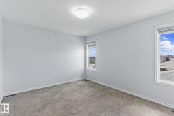 This room features light grey walls, grey carpet flooring, and two windows providing natural light - 