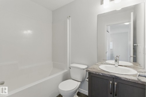 Bathroom featuring a white bathtub and shower surround, a toilet, and a vanity with a sink, faucet, and mirror - 2416 Wonnacott Crest, Edmonton, AB - Indoor Photo Showing Bathroom