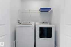 Dedicated laundry area featuring a white washing machine, a white dryer, and an overhead wire shelf - 