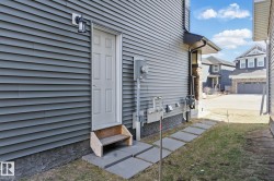 The property features gray siding, a white exterior door, and a wall-mounted light fixture - 
