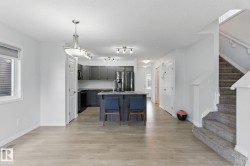 The open concept living area features light-toned flooring, a kitchen with dark cabinetry and stainless steel appliances, and a central island with seating - 