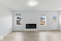 This living space features light-toned flooring, a fireplace, and a door providing exterior access - 