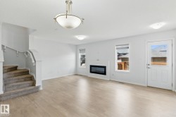 This inviting living area features light-colored flooring, a modern fireplace, and large windows that provide natural illumination - 