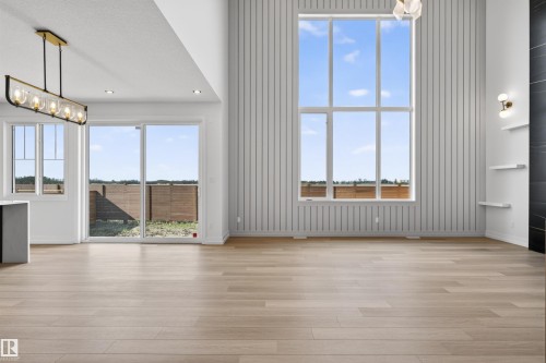 Expansive living space featuring high ceilings, wood-finish flooring, and a floor-to-ceiling window - 63 Jubilation Drive, St. Albert, AB - Indoor Photo Showing Other Room