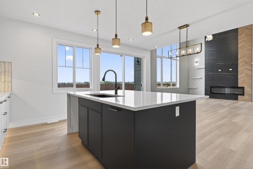 Modern kitchen island featuring a white countertop, undermount sink with a matte black faucet, and black cabinetry - 63 Jubilation Drive, St. Albert, AB - Indoor Photo Showing Kitchen With Upgraded Kitchen