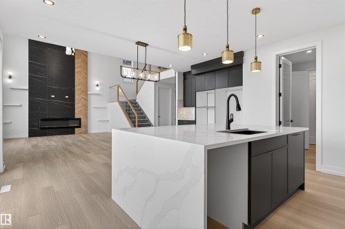 Kitchen island with a waterfall countertop, integrated sink, and matte black faucet - 63 Jubilation Drive, St. Albert, AB - Indoor Photo Showing Kitchen With Upgraded Kitchen