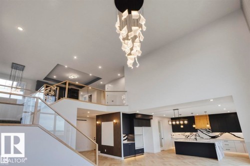 This property features an open-concept layout with a contemporary chandelier, recessed lighting, and a modern kitchen with a large island and accent lighting - 63 Jubilation Drive, St. Albert, AB - Indoor Photo Showing Other Room