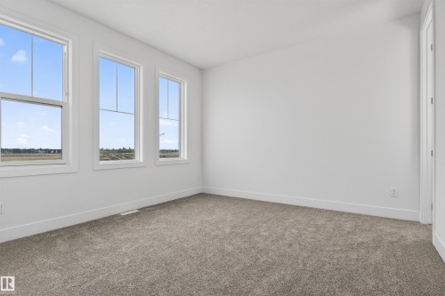 Carpeted room featuring three windows with white frames and trim, white walls, and white baseboards - 63 Jubilation Drive, St. Albert, AB - Indoor Photo Showing Other Room