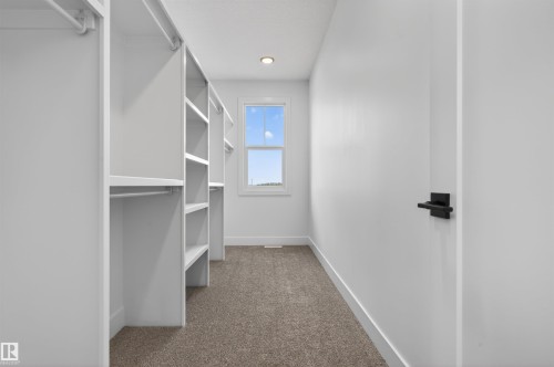 Walk-in closet featuring built-in shelving, hanging rods, recessed lighting, and a single window - 63 Jubilation Drive, St. Albert, AB - Indoor