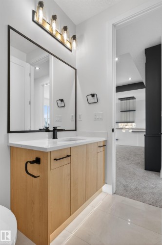 Contemporary bathroom featuring a wood-finish vanity with a white countertop and undermount sink, complemented by a matte black faucet - 63 Jubilation Drive, St. Albert, AB - Indoor