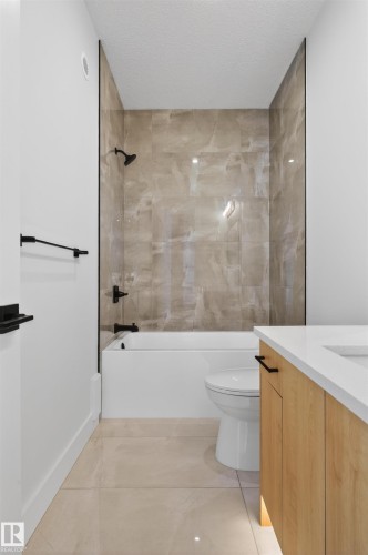 Bathroom featuring a tub/shower combination with large format tiled walls and matte black fixtures - 63 Jubilation Drive, St. Albert, AB - Indoor Photo Showing Bathroom