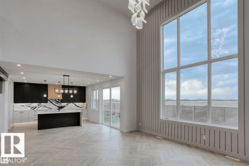 Spacious living area featuring high ceilings, large windows with expansive views, and herringbone pattern flooring - 63 Jubilation Drive, St. Albert, AB - Indoor Photo Showing Other Room