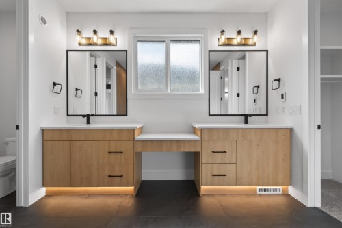 Double vanity with wood-finish cabinetry, quartz countertops, and undersink lighting - 63 Jubilation Drive, St. Albert, AB - Indoor Photo Showing Other Room