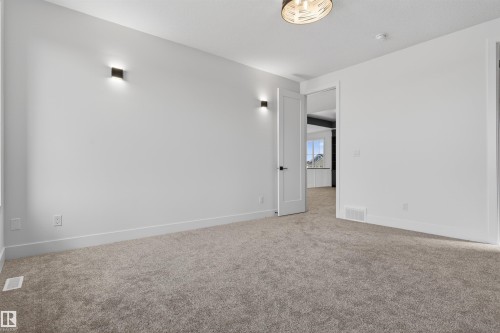 Spacious room with plush gray carpeting, crisp white walls, and contemporary wall sconces - 63 Jubilation Drive, St. Albert, AB - Indoor Photo Showing Other Room