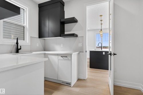 Modern kitchen featuring white cabinetry, light countertops, and a black faucet - 63 Jubilation Drive, St. Albert, AB - Indoor