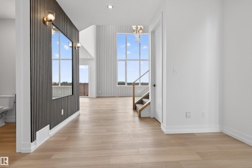 Expansive living area featuring light wood-finish flooring, soaring ceilings, and large grid-pattern windows - 63 Jubilation Drive, St. Albert, AB - Indoor Photo Showing Other Room