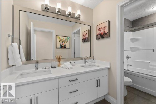 Bathroom featuring a Double Vanity with White Cabinetry, Quartz Counters, and Bathtub with Wall Surround Kit - 4476 Suzanna Crescent, Edmonton, AB - Indoor Photo Showing Bathroom