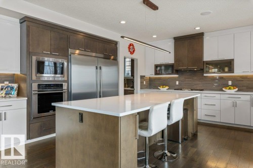Kitchen Features Dark Hardwood Flooring, Two Tone Kitchen Cabinets, Gas Stove, Wall Oven, and White Quartz Counters - 4476 Suzanna Crescent, Edmonton, AB - Indoor Photo Showing Kitchen With Upgraded Kitchen